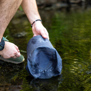 Guy holding blue cap in stream