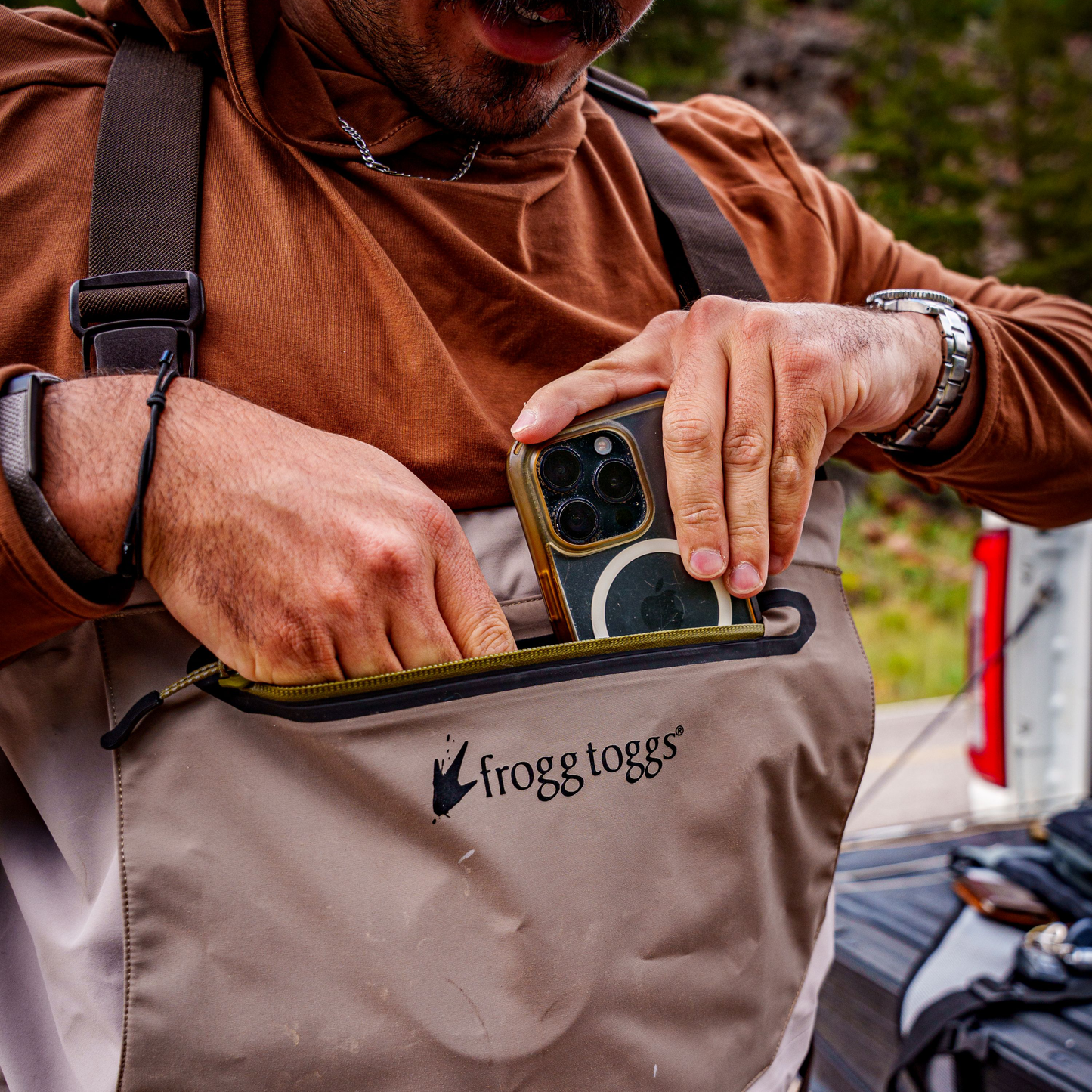 Person using a phone with a frogg toggs wader outdoors