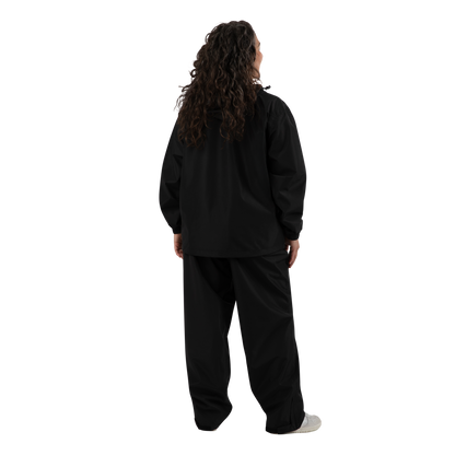 A person shown from the back wearing a black long-sleeve top and matching black pants, standing against a plain white background.