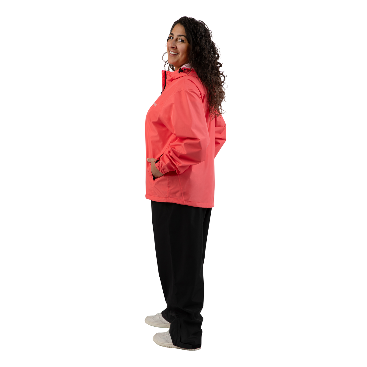 A woman modeling a coral pink hooded jacket, paired with black pants and white shoes, shown in a side profile against a solid white background.