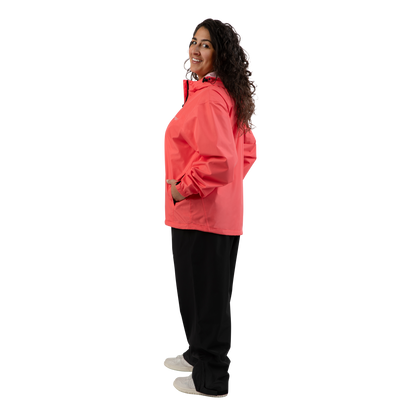 A woman modeling a coral pink hooded jacket, paired with black pants and white shoes, shown in a side profile against a solid white background.