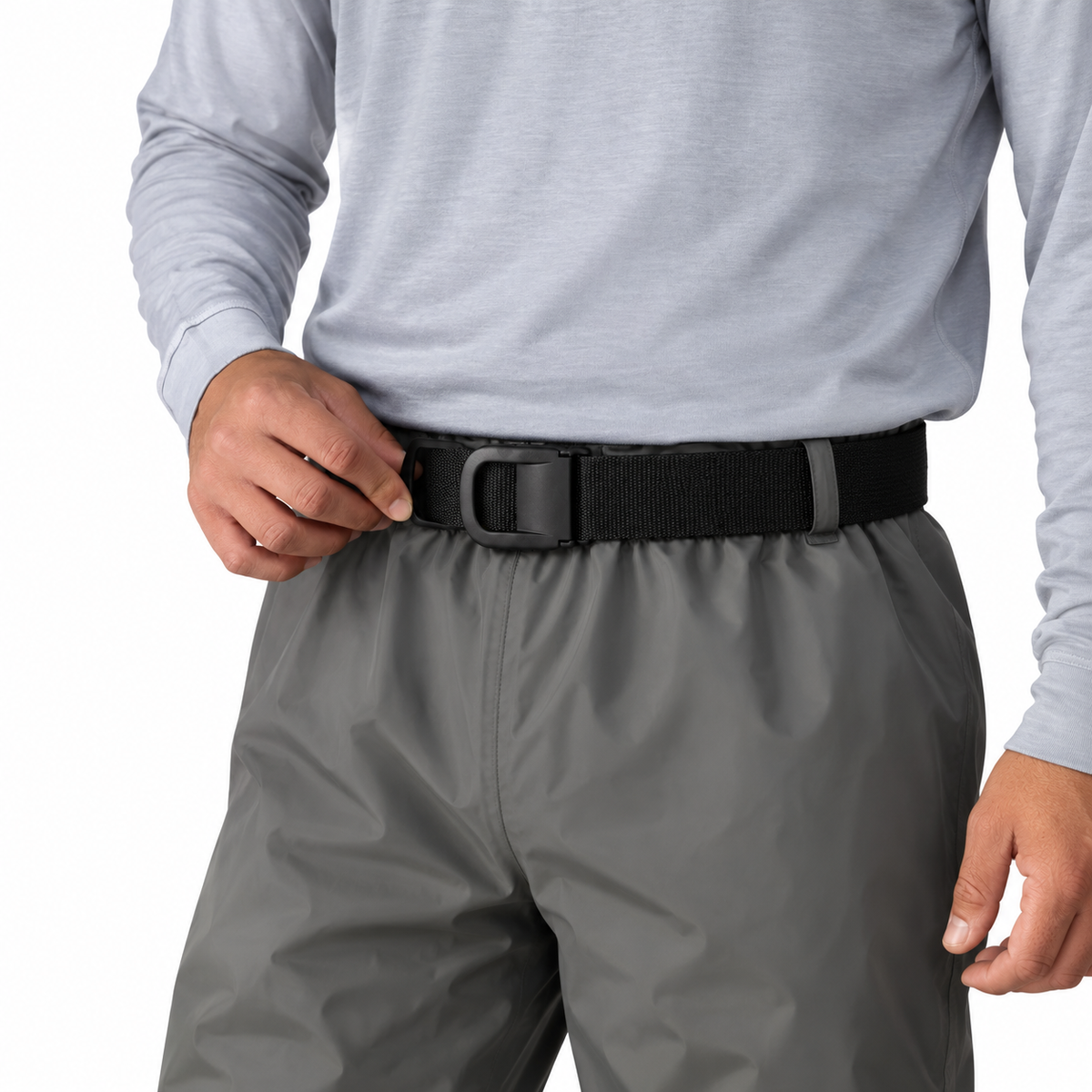 A close-up of a person wearing a black Frogg Toggs wading belt with a black buckle, paired with a light gray long-sleeve shirt and gray pants, against a plain white background.