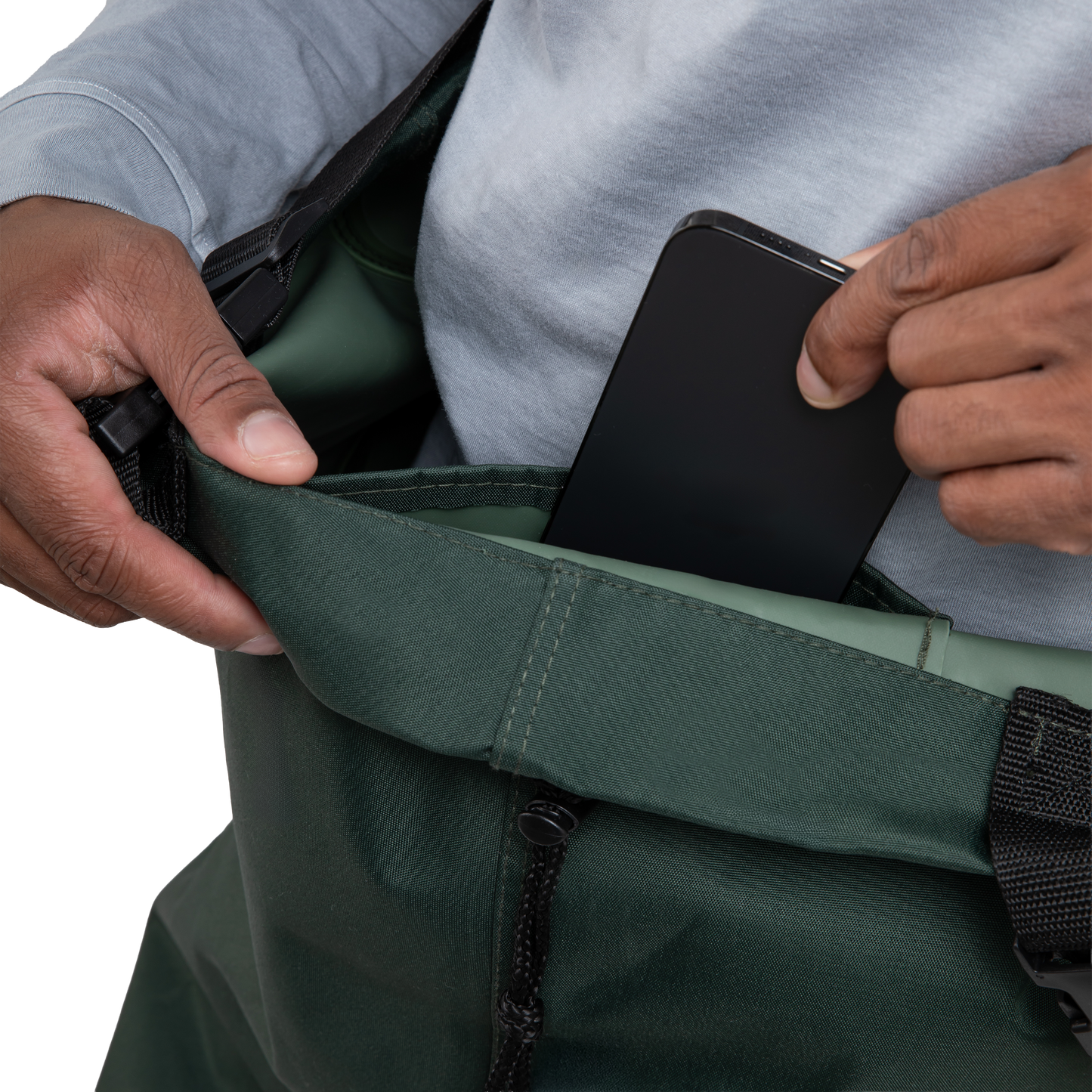 Person placing a black phone into a green bag