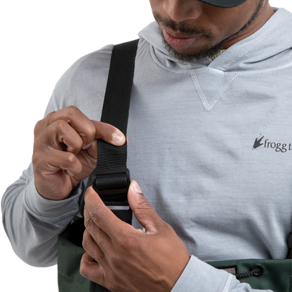 Person adjusting a strap on a bag, wearing a gray hoodie with a brand logo.