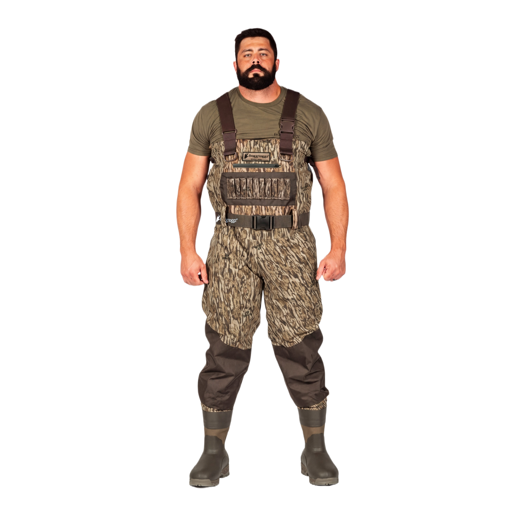 A man modeling a pair of camouflage chest waders with brown suspenders, an olive green t-shirt, and dark rubber boots, set against a plain white background.