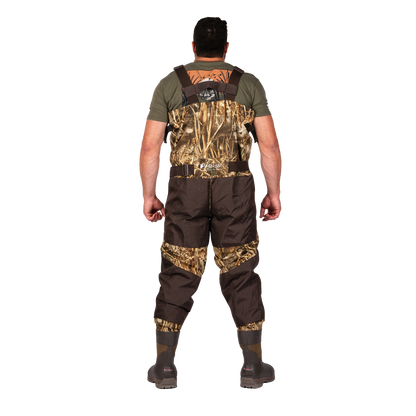 A man viewed from the back wearing a pair of camouflage and brown waders over an olive green t-shirt, standing against a solid white background.
