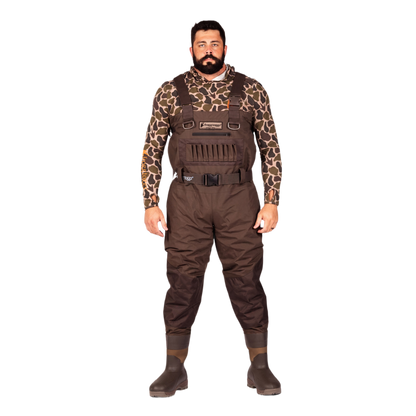 A man modeling brown waterproof waders over a brown and black giraffe-print long-sleeve shirt, standing against a solid white background.