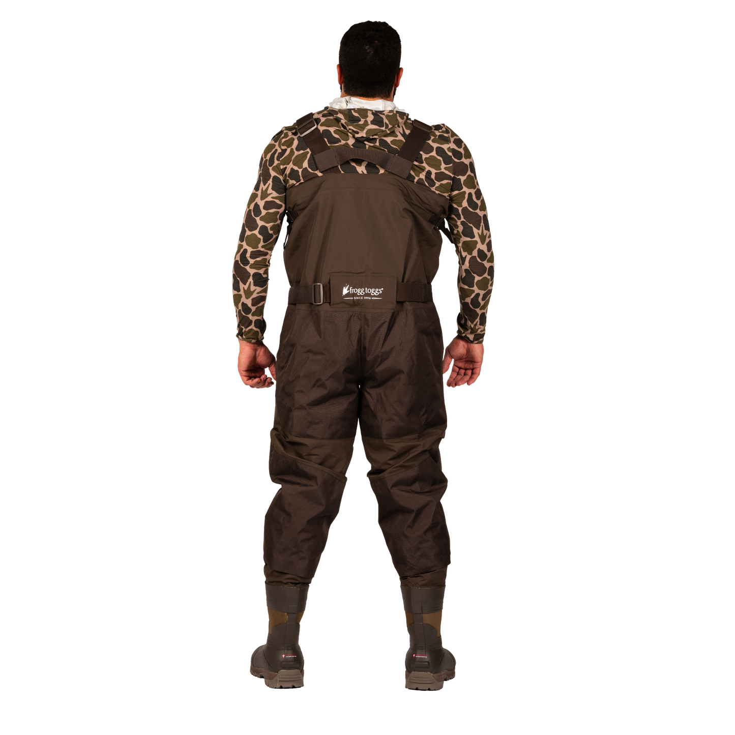 A man viewed from the back wearing brown waders over a long-sleeve camouflage shirt, standing against a plain white background.