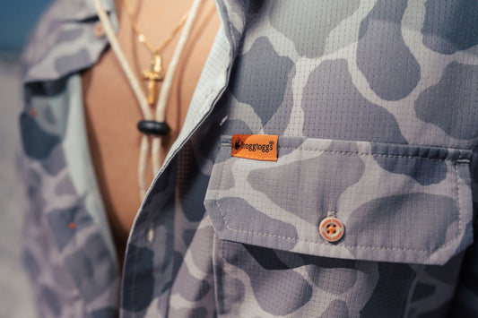 Close-up of a person wearing a patterned shirt with a brand label, blurred background