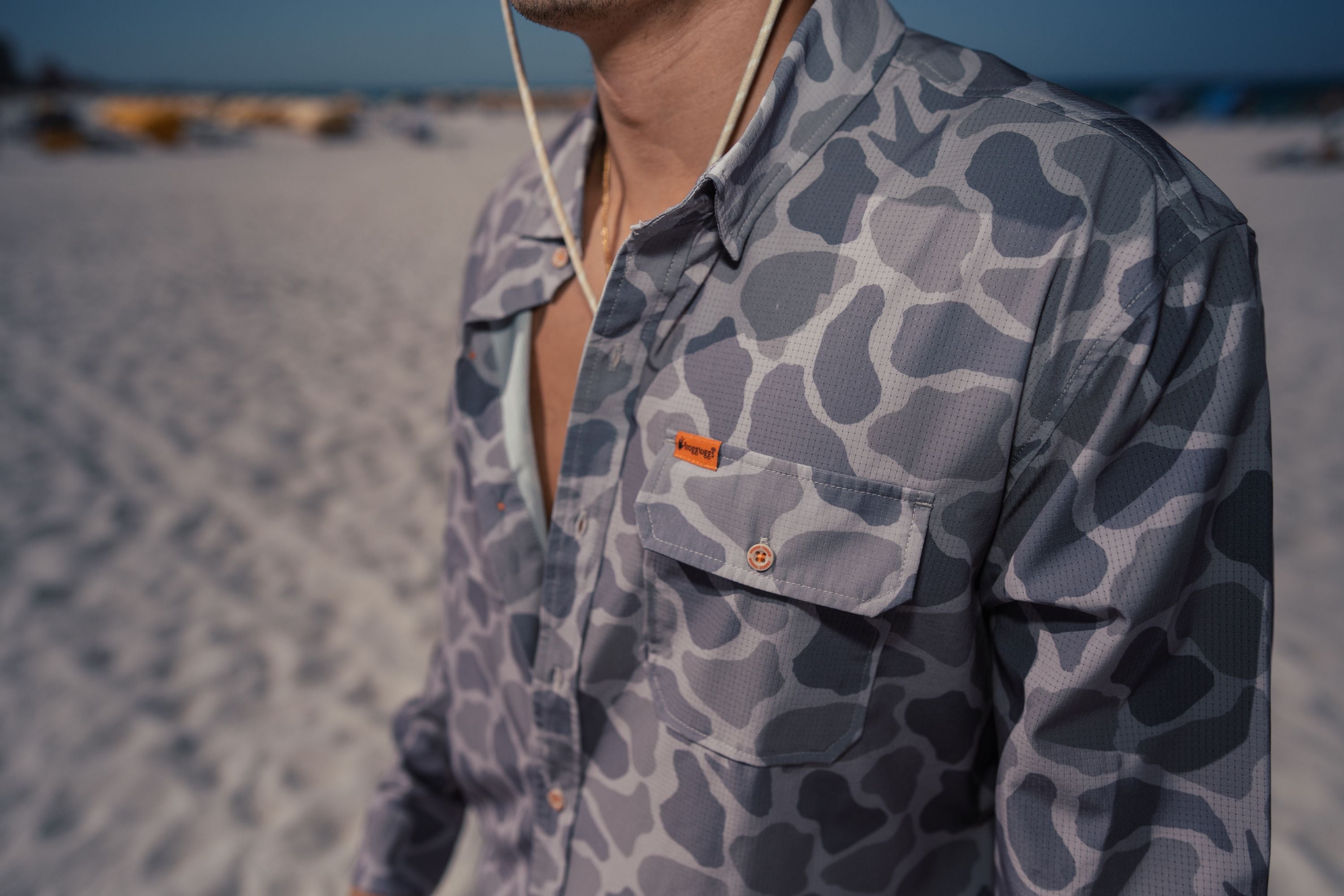 Person wearing a retro camo patterned shirt on a beach