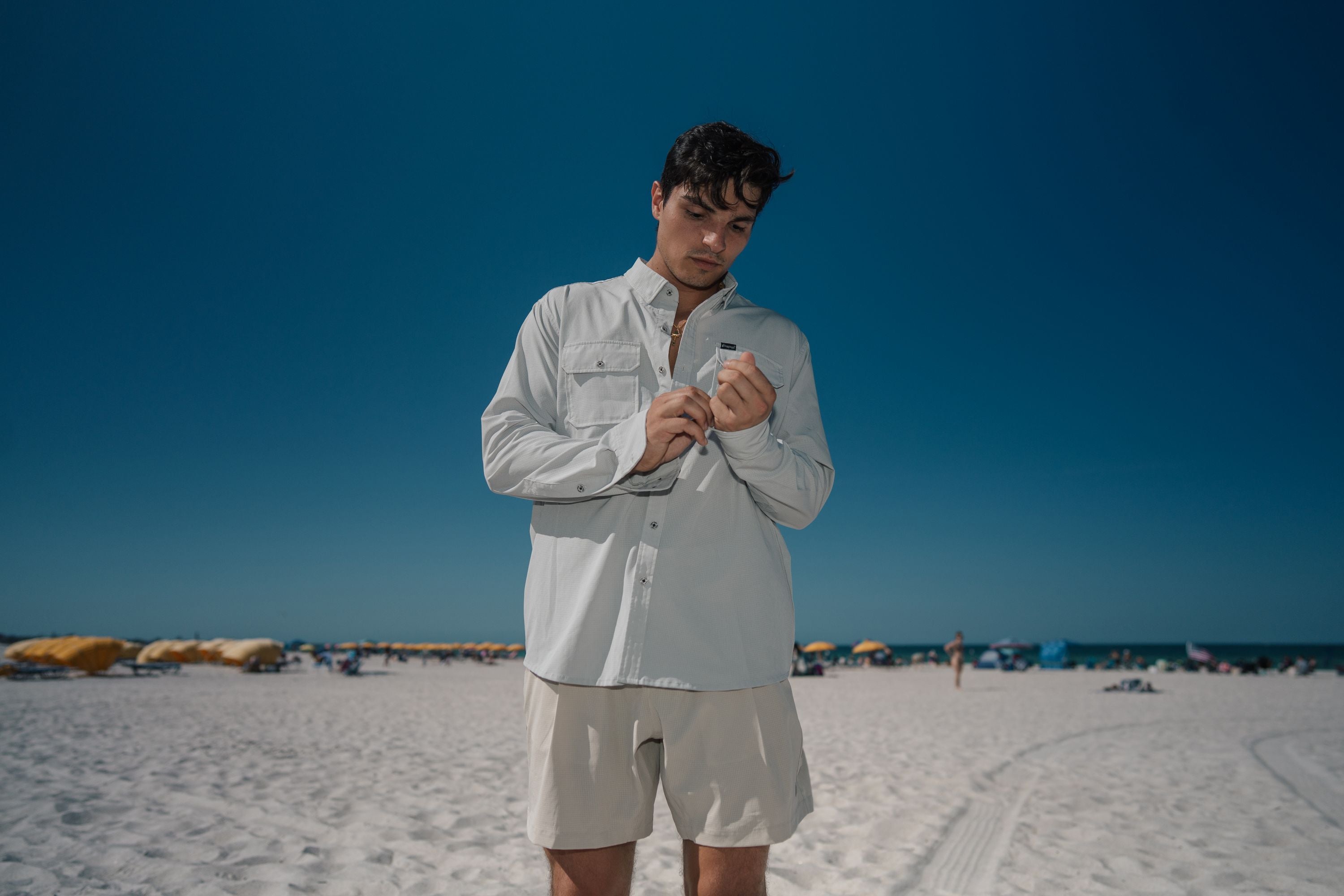 Man standing on a sandy beach with clear blue sky