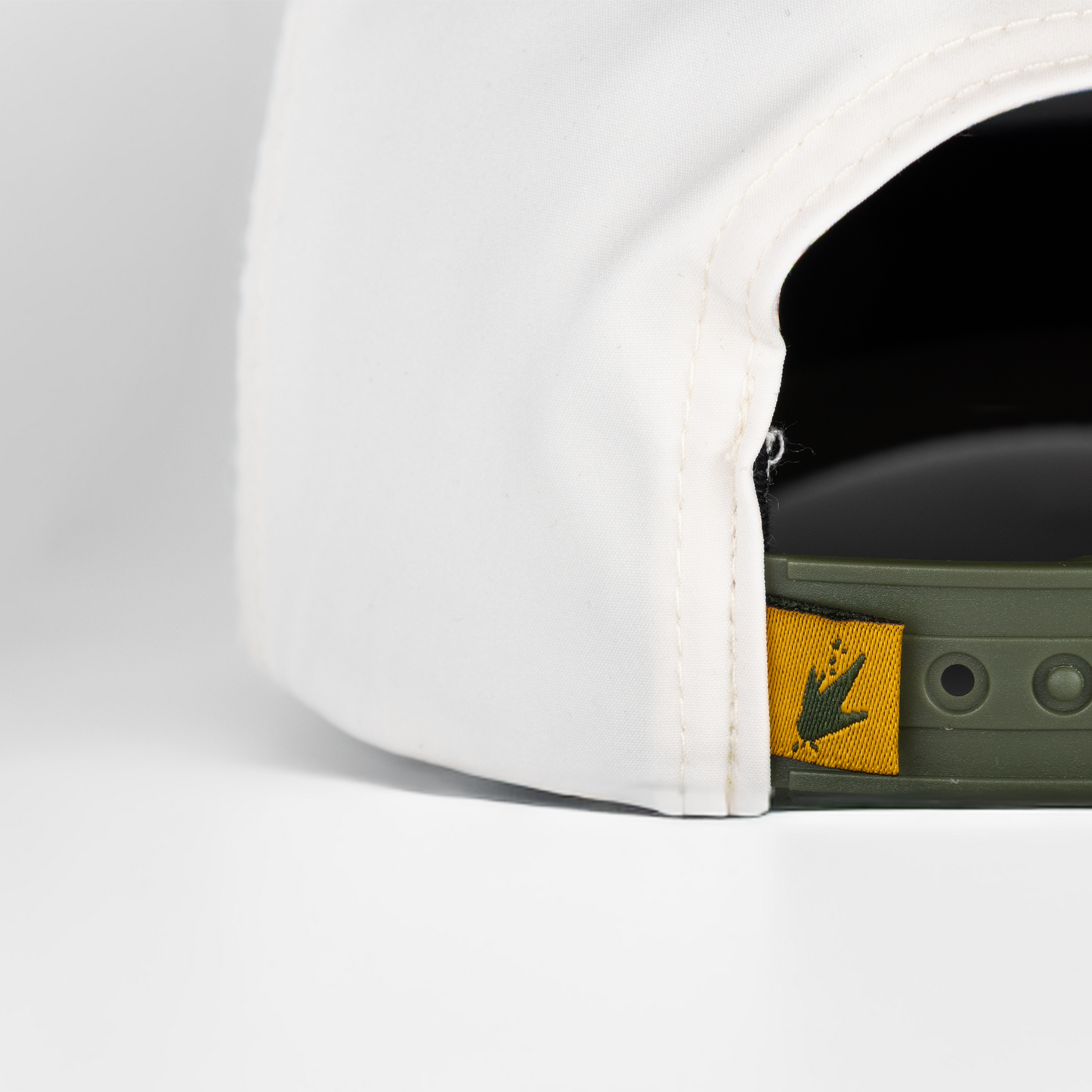 Close-up of a white cap with a yellow and green logo on a light gray background
