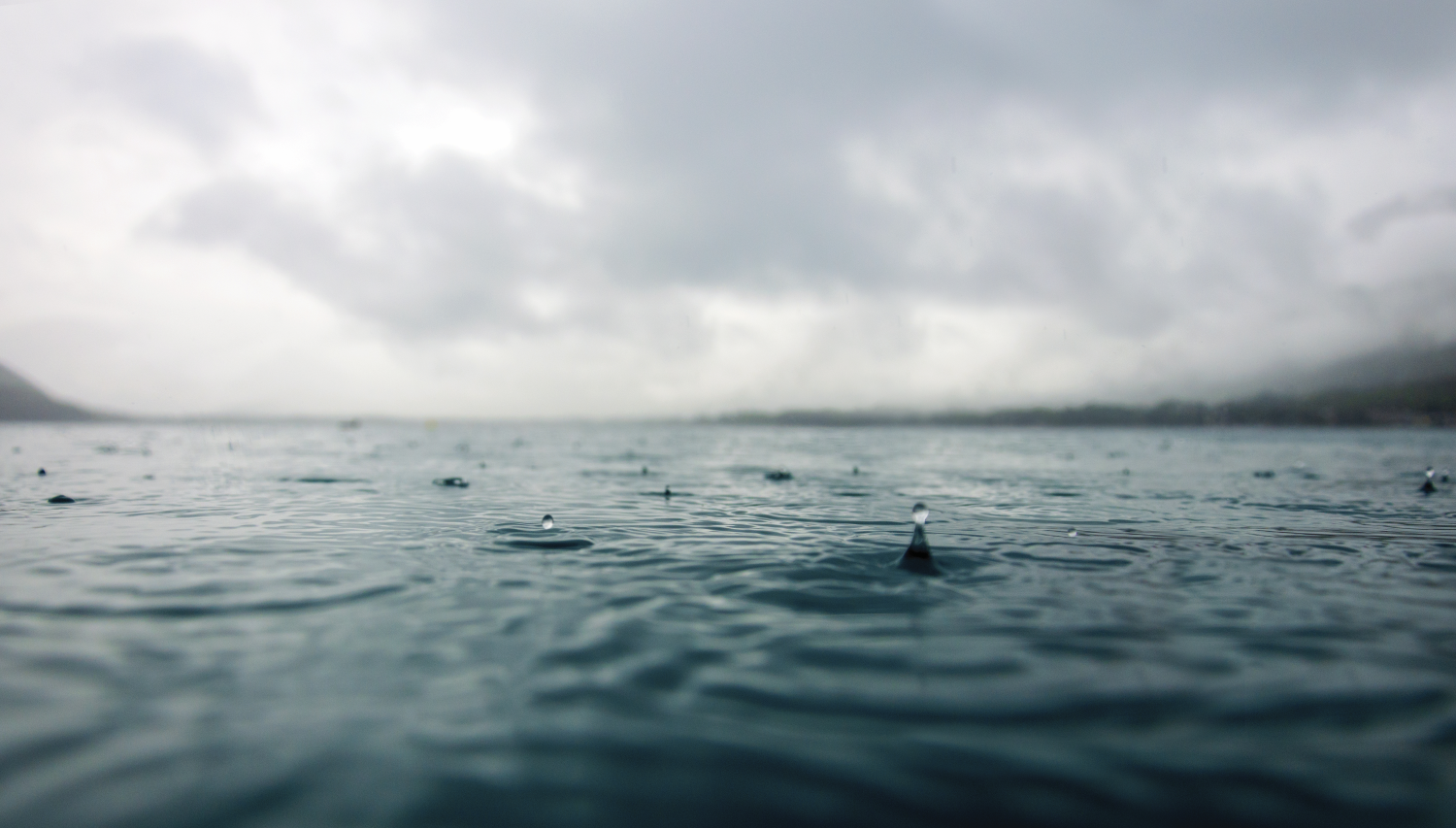 Distant view of a mountain range shrouded in mist over a lake.