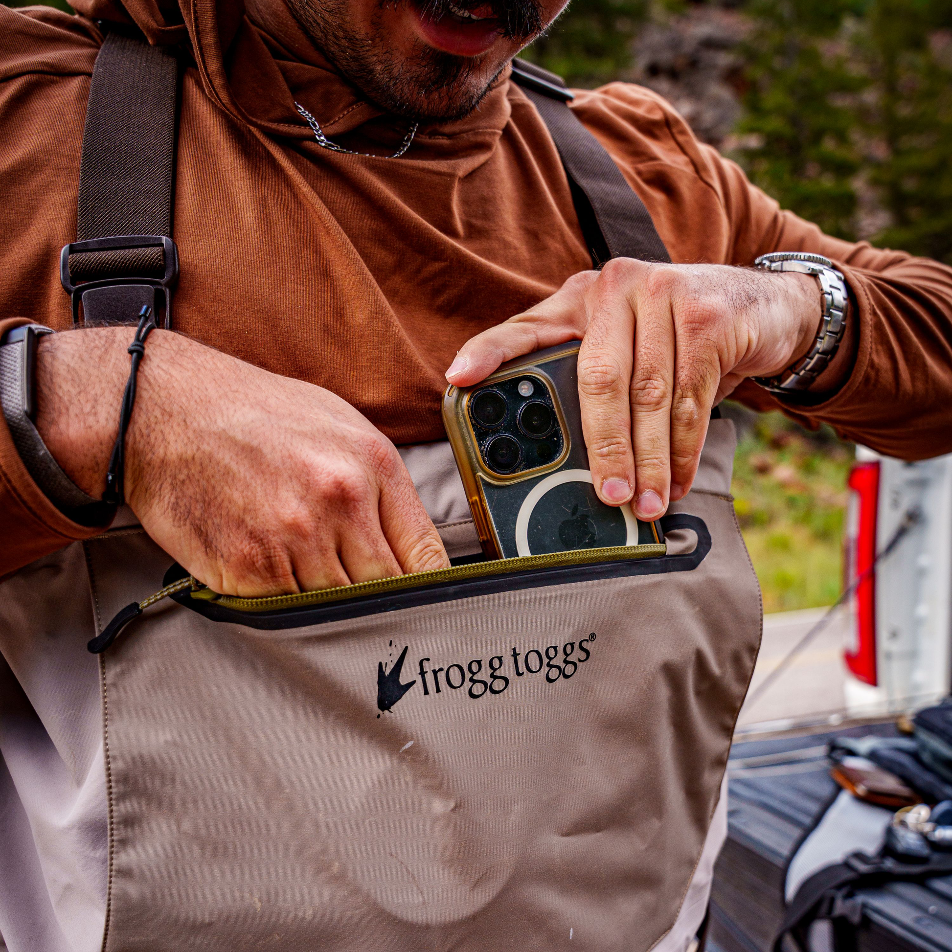 Person using a phone with a frogg toggs wader outdoors