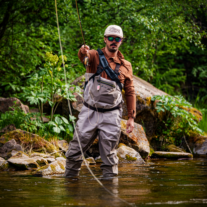 Man fly fishing in a stream surrounded by greenery