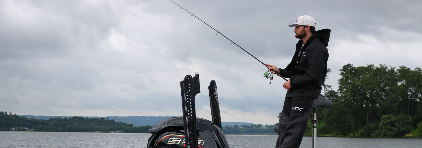 Man fishing on a boat with a cloudy sky in the background