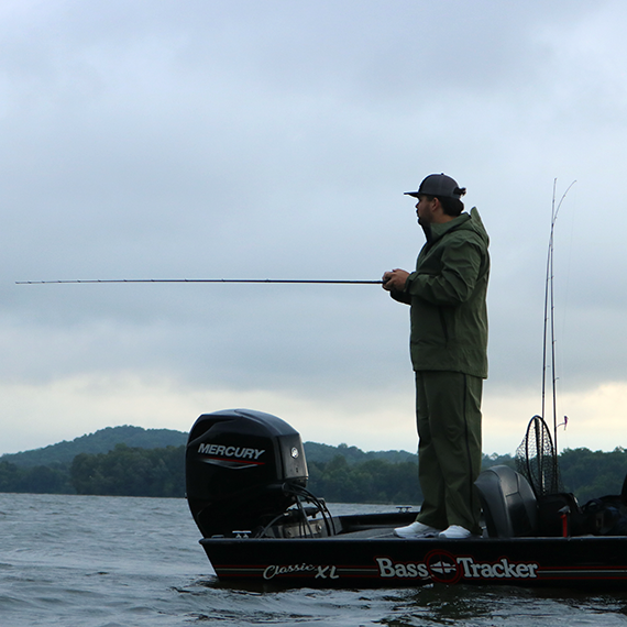 Man fishing from a boat on a lake with a cloudy sky